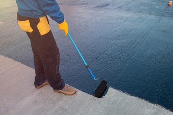Roofer applying roof coating in Fort Hamilton, NY